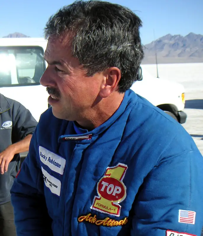 Rocky Robinson wearing a blue motorcycle jacket seen from a side profile up close.