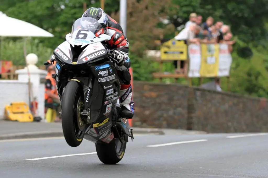 Photo from the Isle of Man TT showing a competitor on a BMW S 1000R superbike racing in the event. His front tyre is in the air